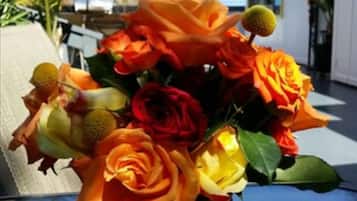Un jarrón con rosas anaranjadas y amarillas sobre una superficie reflectante.