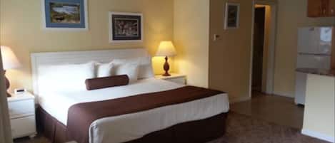 A hotel room with a bed, bedside table, lamp, and a remote control on a small table.