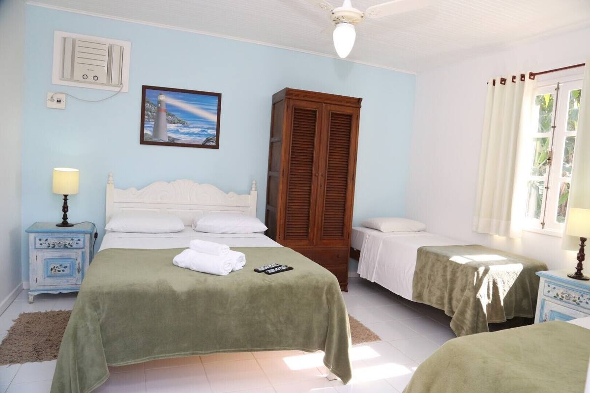 Ein Schlafzimmer mit zwei Betten, einem Holzschrank, einem Gemälde eines Leuchtturms und einem Deckenventilator.