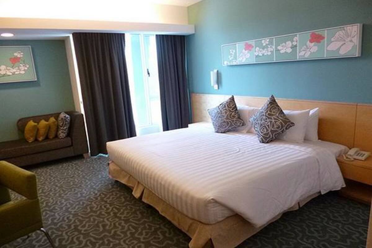 Una habitación de hotel con una cama grande, un sofá, un teléfono y una pared decorada con motivos florales.