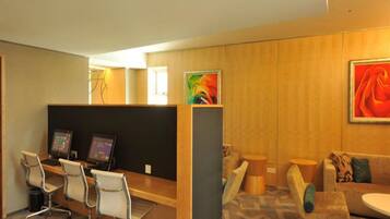 A modern hotel lobby with a reception desk, several chairs, a sofa, and artwork on the walls.