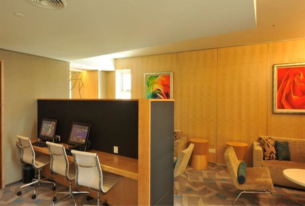 A modern hotel lobby with a reception desk, several chairs, a sofa, and artwork on the walls. - The Everly Putrajaya (Putrajaya)