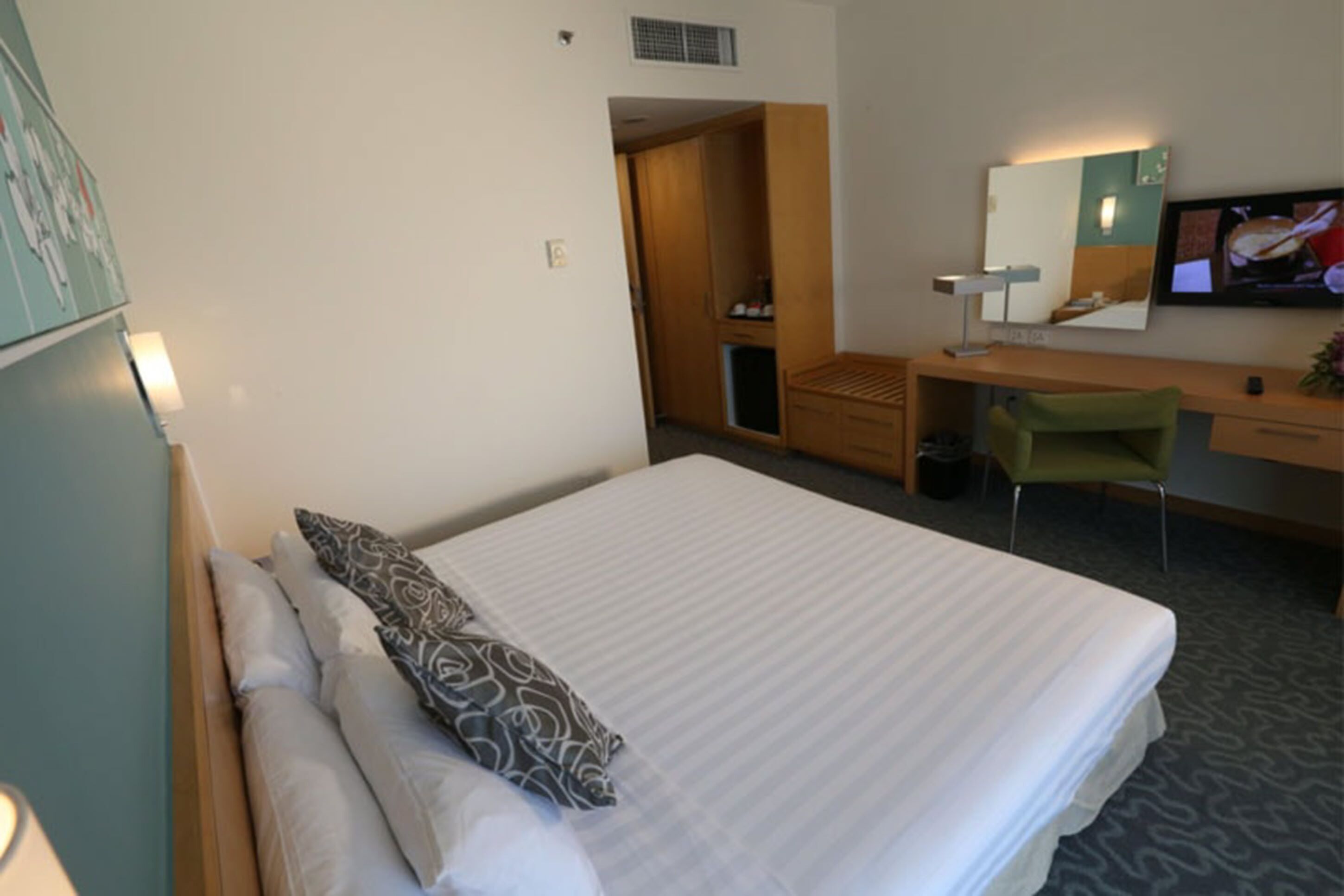 Una habitación de hotel con cama, escritorio, silla, televisor y armario.