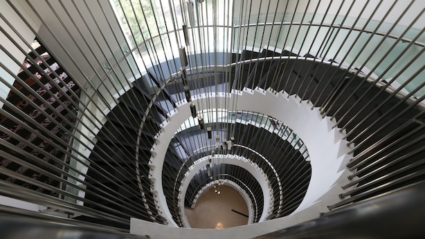 Un escalier en colimaçon au design moderne, doté de rampes en verre et de balustrades en métal.