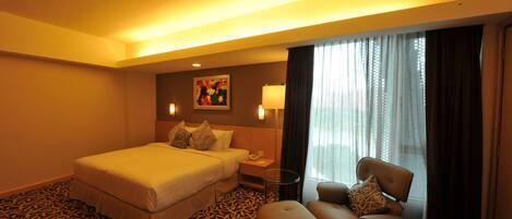 A hotel room with a large bed, a desk with a chair, a lamp, and a painting on the wall.