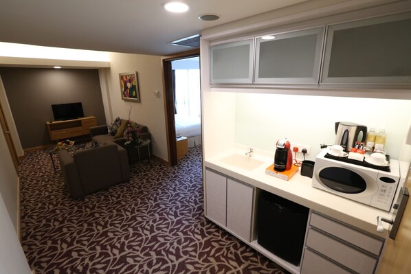 A compact hotel room with a kitchenette, a sofa, a dining area, and a patterned carpet. - The Everly Putrajaya (Putrajaya)