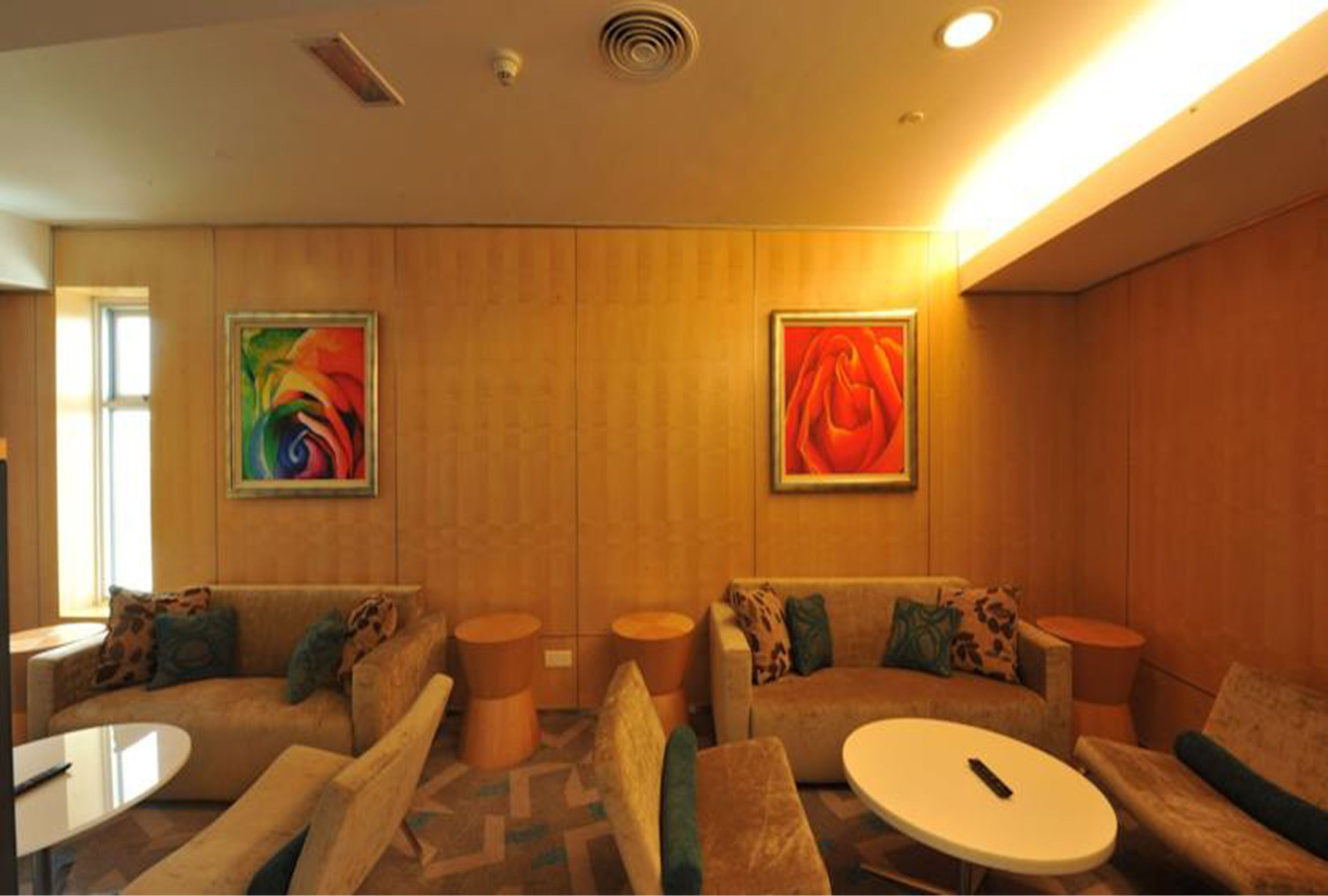 Een moderne woonkamer met een zithoek, een salontafel en twee bijzettafels. Twee abstracte schilderijen hangen aan de muur.