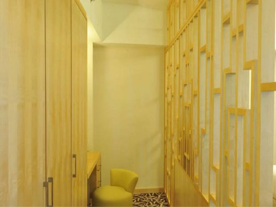 A narrow hallway with wooden doors and a yellow chair.