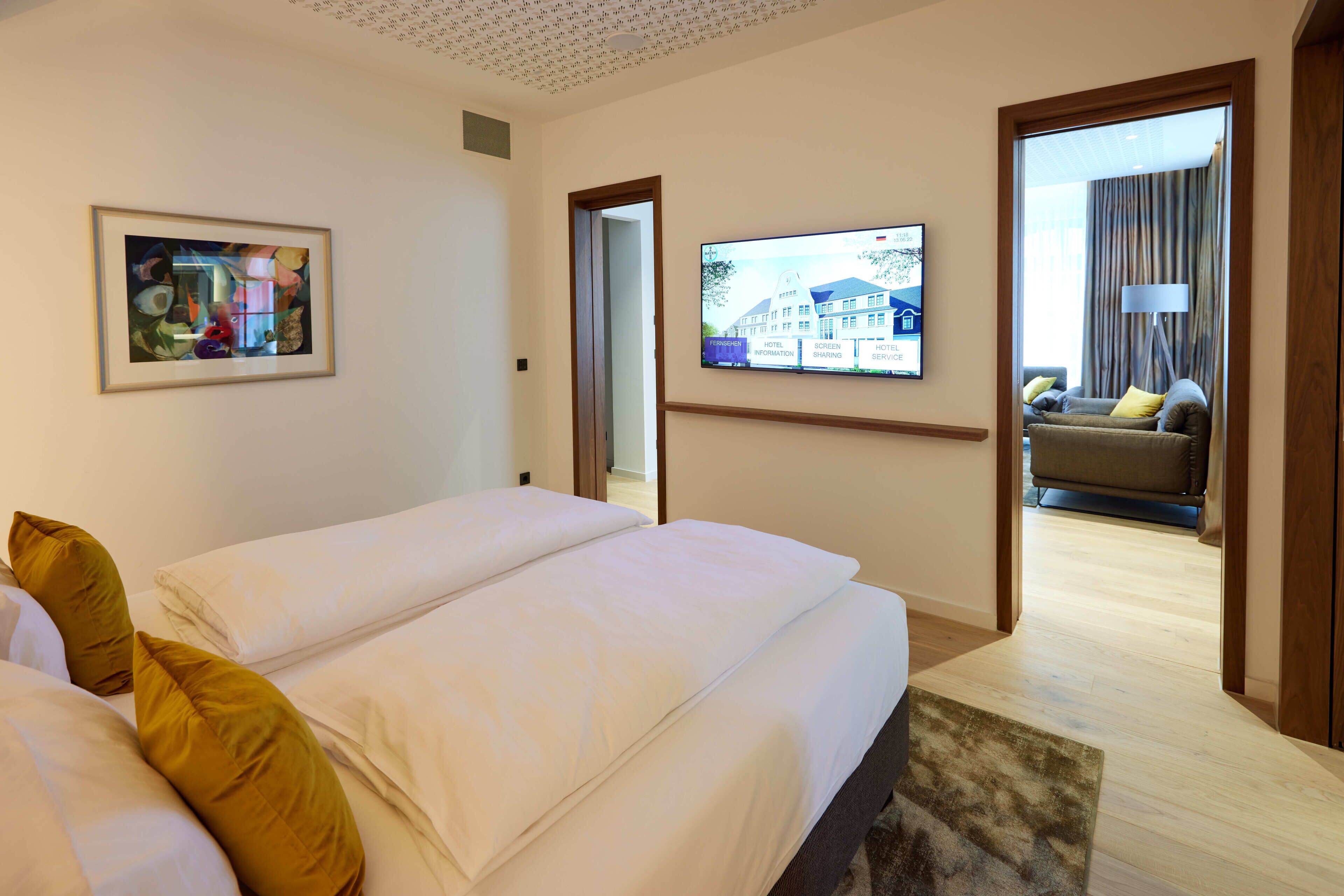 Une chambre d’hôtel avec un grand lit, un téléviseur fixé au mur et une vue sur le balcon extérieur.