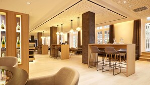 A modern bar area with high stools, a counter, and a wine display. - Kasino Hotel (Leverkusen)