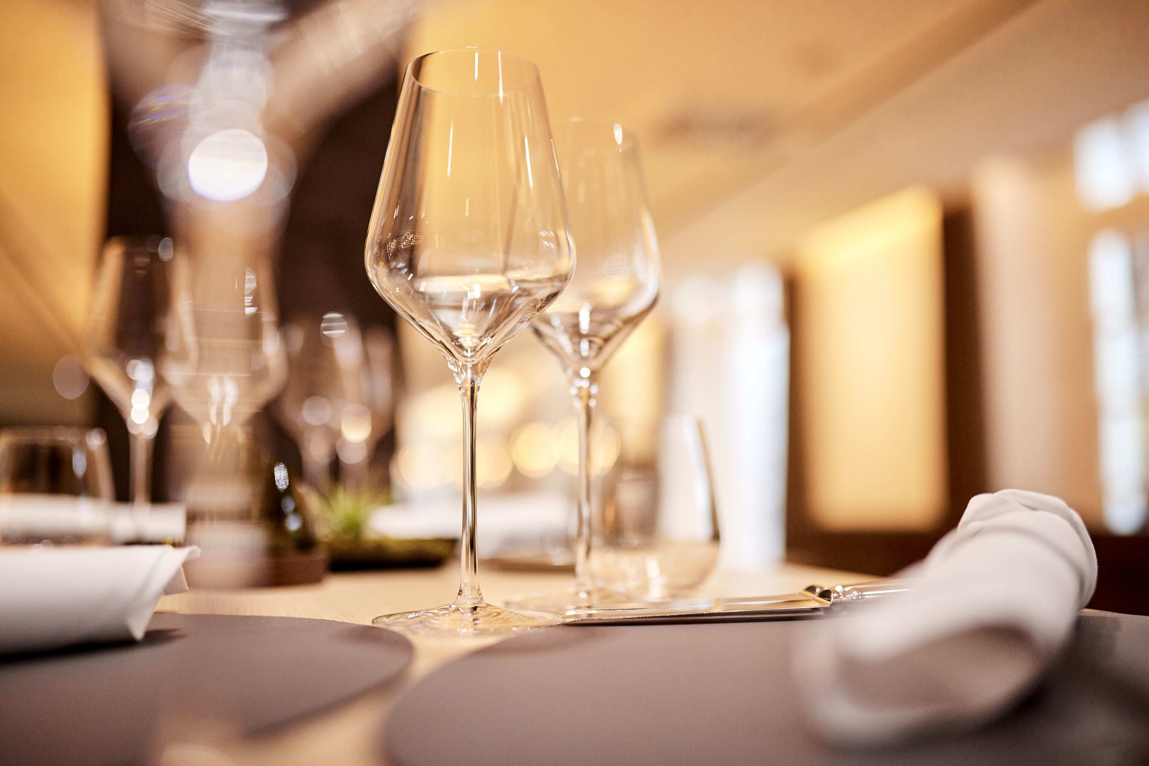 A dining table with empty wine glasses and a folded napkin.