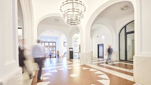 A spacious lobby with a geometric patterned floor, arched ceilings, and a central chandelier. - Kasino Hotel (Leverkusen)
