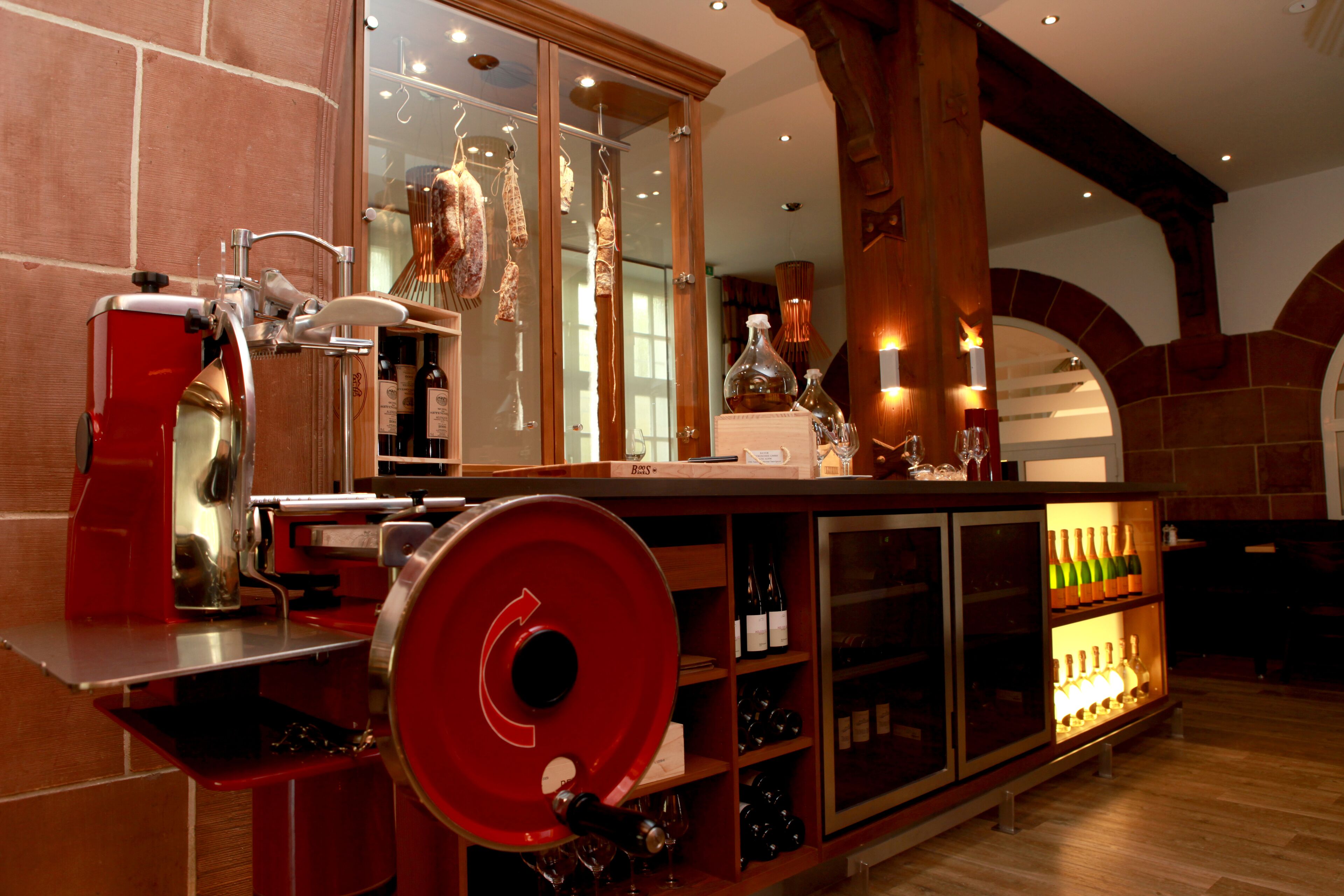 A bar area with a wine rack, a red wine cooler, and a wine bottle on the counter.