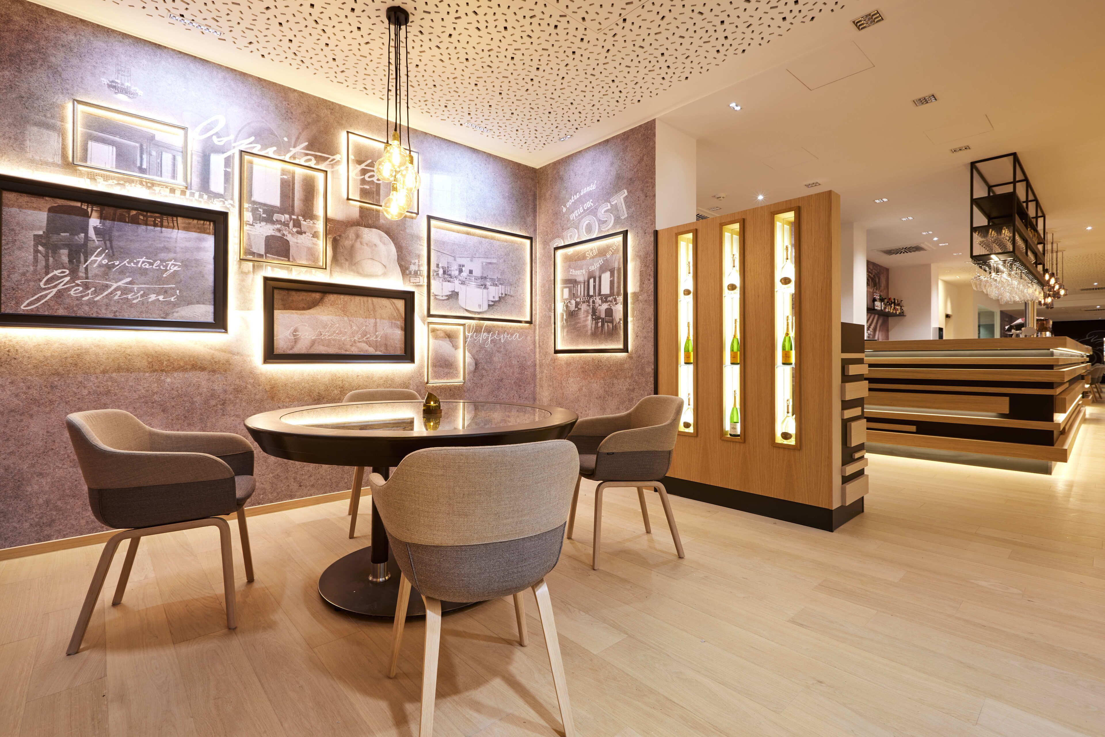Un comedor moderno con una mesa redonda y cuatro sillas, fotografías enmarcadas en la pared y un mostrador de recepción de madera.