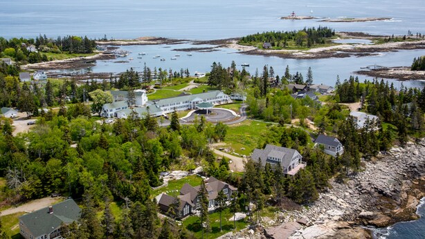 An aerial view of a coastal property with a large house, a circular driveway, and a view of the ocean. - Newagen Seaside Inn (Southport)