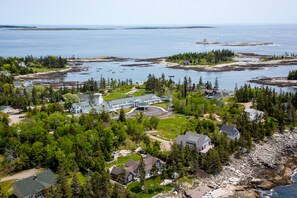 An aerial view of a coastal property with a large house, a circular driveway, and a view of the ocean. - Newagen Seaside Inn (Southport)