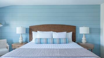 Un dormitorio con una cama grande, dos mesitas de noche, un cabecero de mimbre y una pared azul.