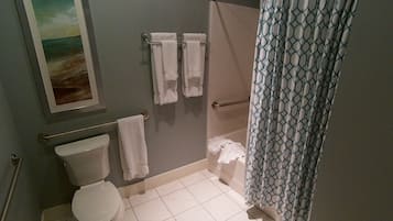 Une salle de bain avec des toilettes, une douche dotée d’un rideau à motifs et un porte-serviettes avec des serviettes.