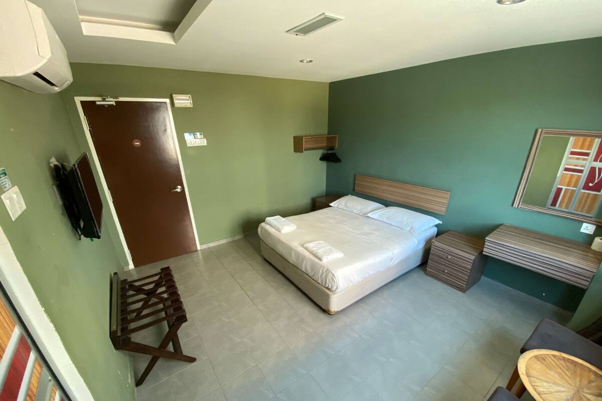 Ein Schlafzimmer mit einem Bett, Nachttischen, einem Sessel, einem Spiegel und einer Tür.