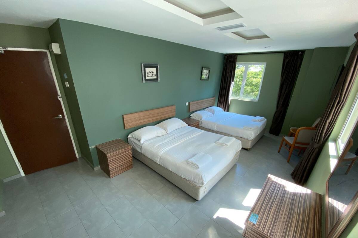 Ein Schlafzimmer mit zwei Betten, einem Holznachttisch, einem Stuhl und einem Fenster mit Vorhängen.