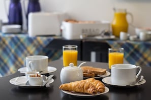 A breakfast table with croissants, coffee cups, and orange juice.