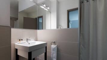 Un baño moderno con lavamanos, espejo y cortina de ducha blancos.