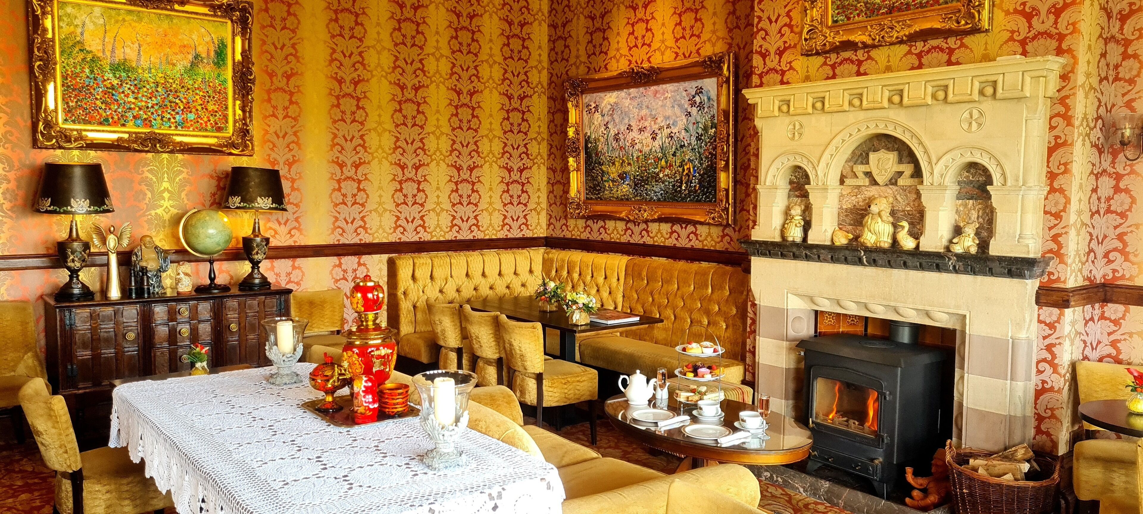 A cozy room with a fireplace, a dining table set for tea, and a comfortable sofa.