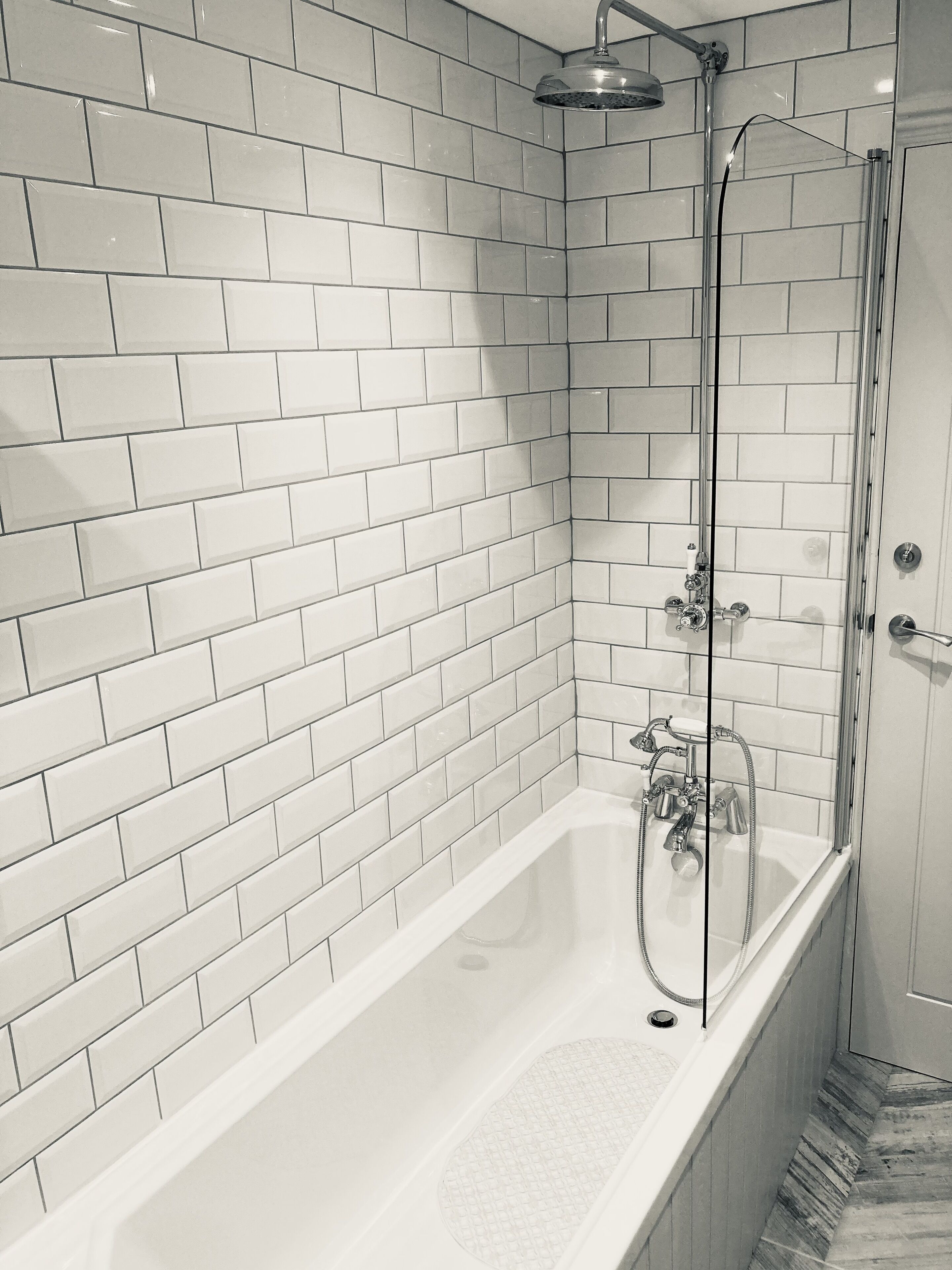 A modern bathroom with white subway tiles, a glass-enclosed shower, and a freestanding bathtub.