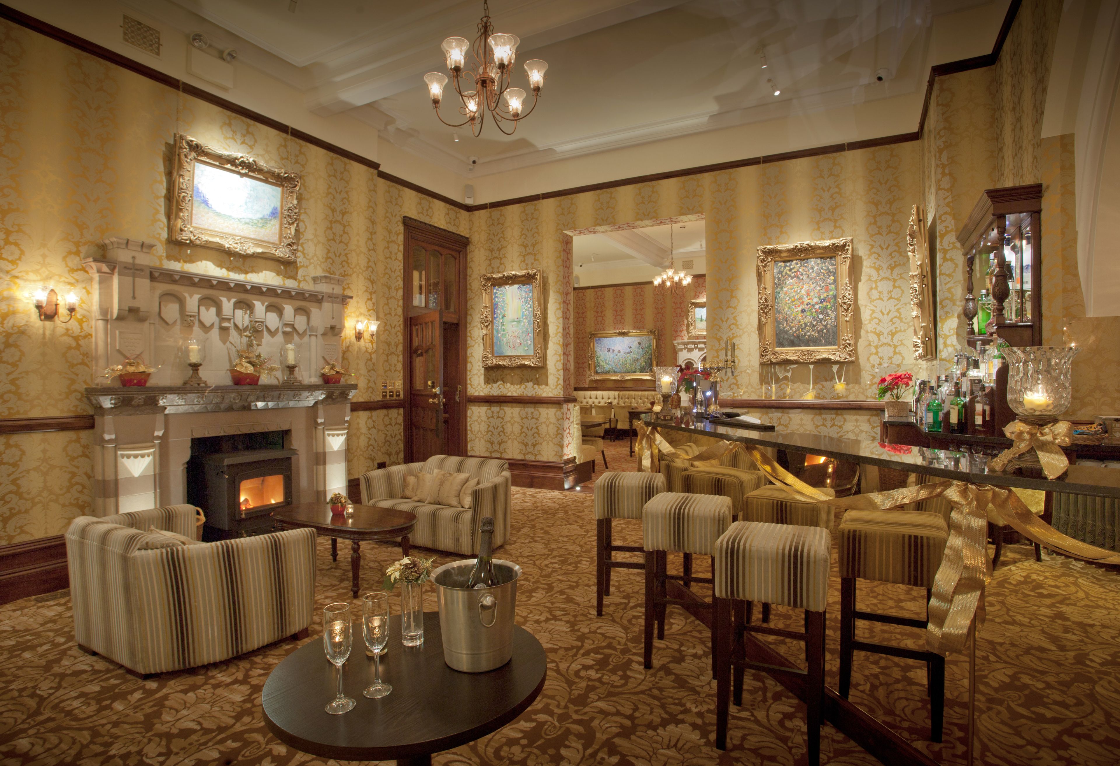 A luxurious hotel lobby with a fireplace, comfortable seating, a bar area, and a television.