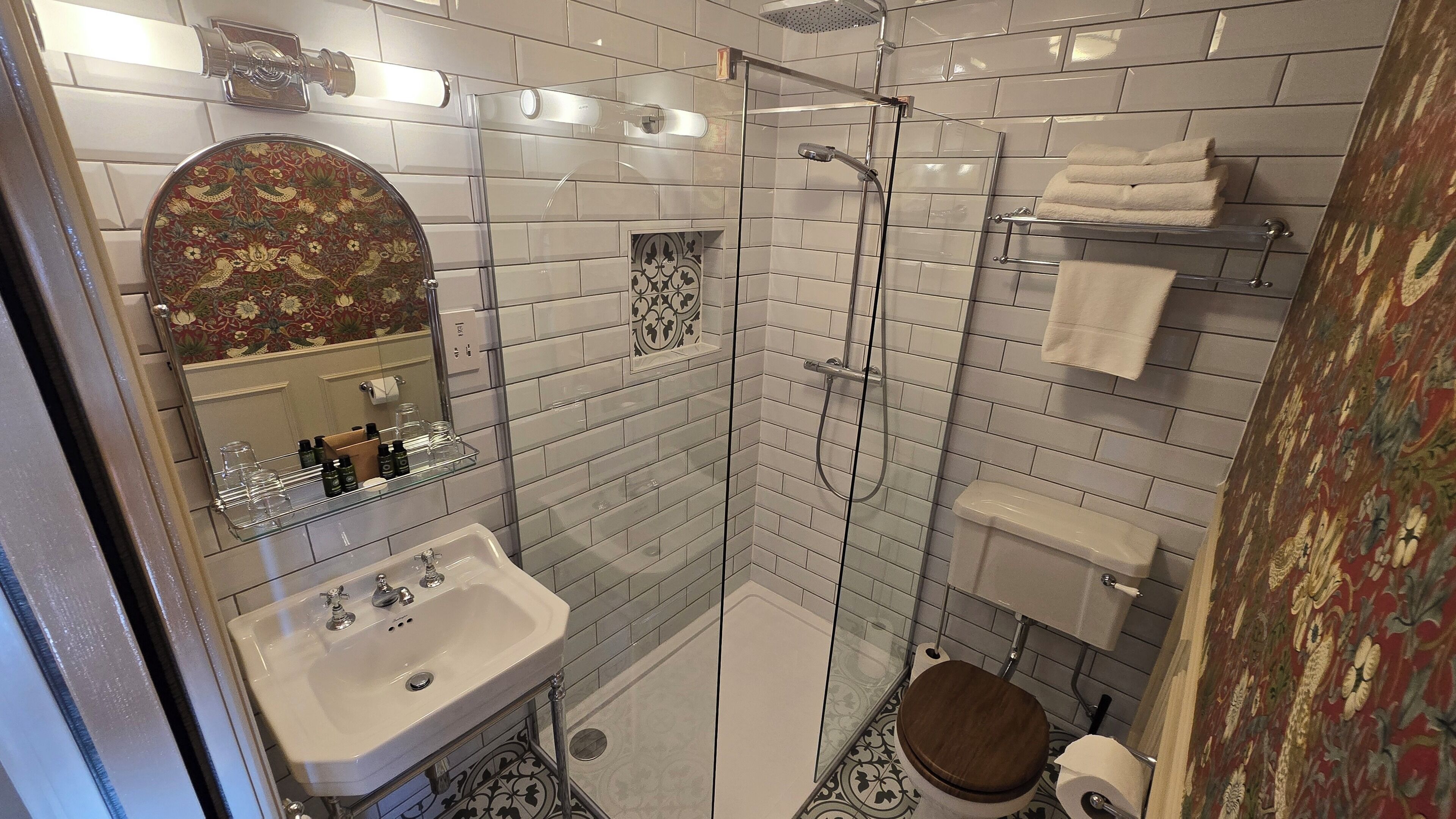 A bathroom with a glass-enclosed shower, a sink with a mirror, and a toilet.