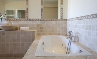 Un baño moderno con una bañera independiente, un lavabo grande y un perchero para toallas.