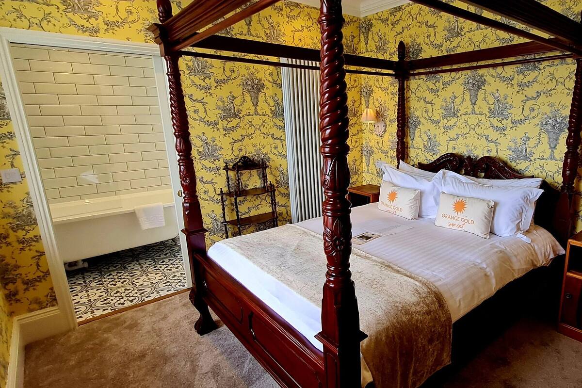 A four-poster bed with a canopy, a bedside table, and a nightstand.