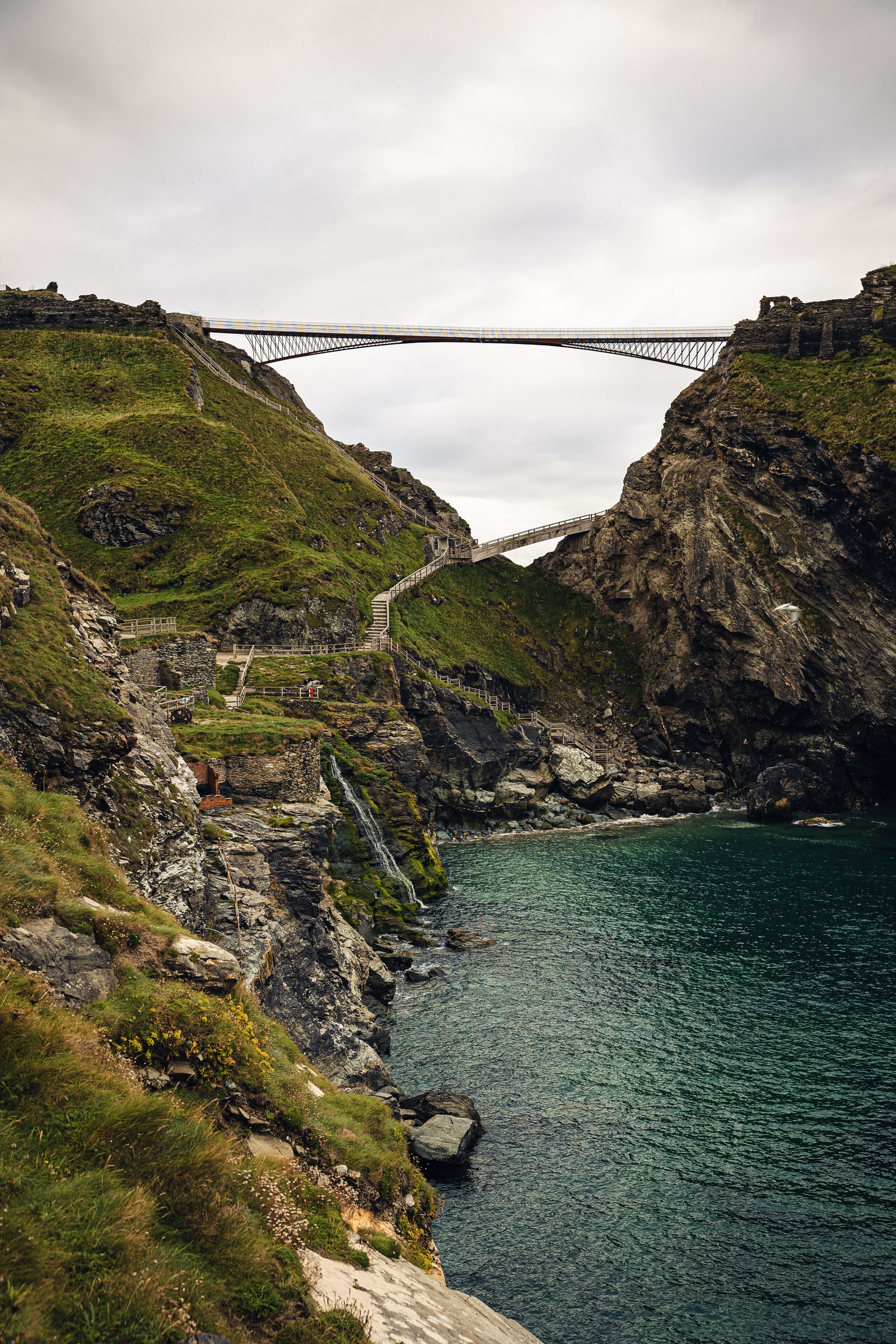 Un pont enjambant une côte rocheuse, avec une cascade.