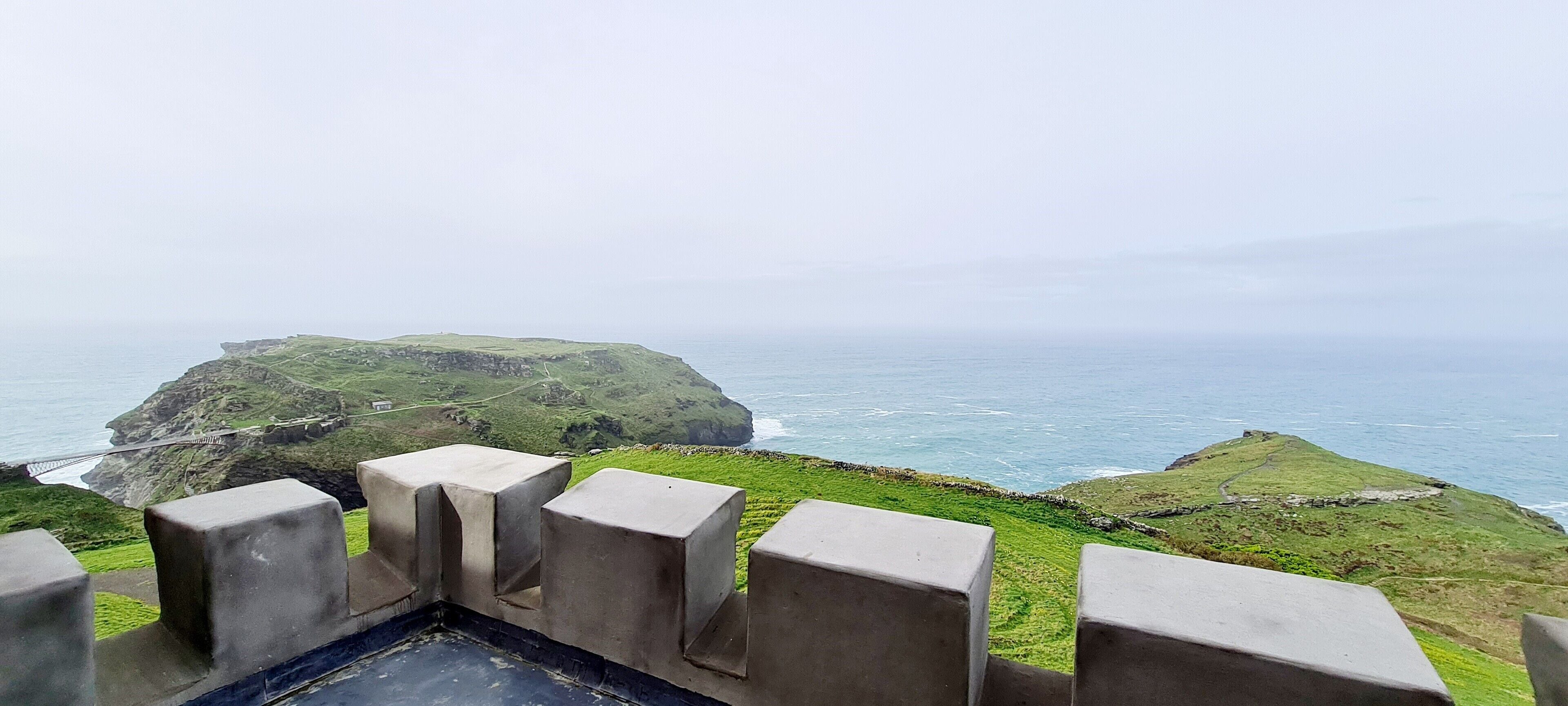 A coastal landscape with a grassy hill and a sea view.