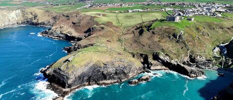 A coastal landscape with rocky cliffs, a village, and a castle.