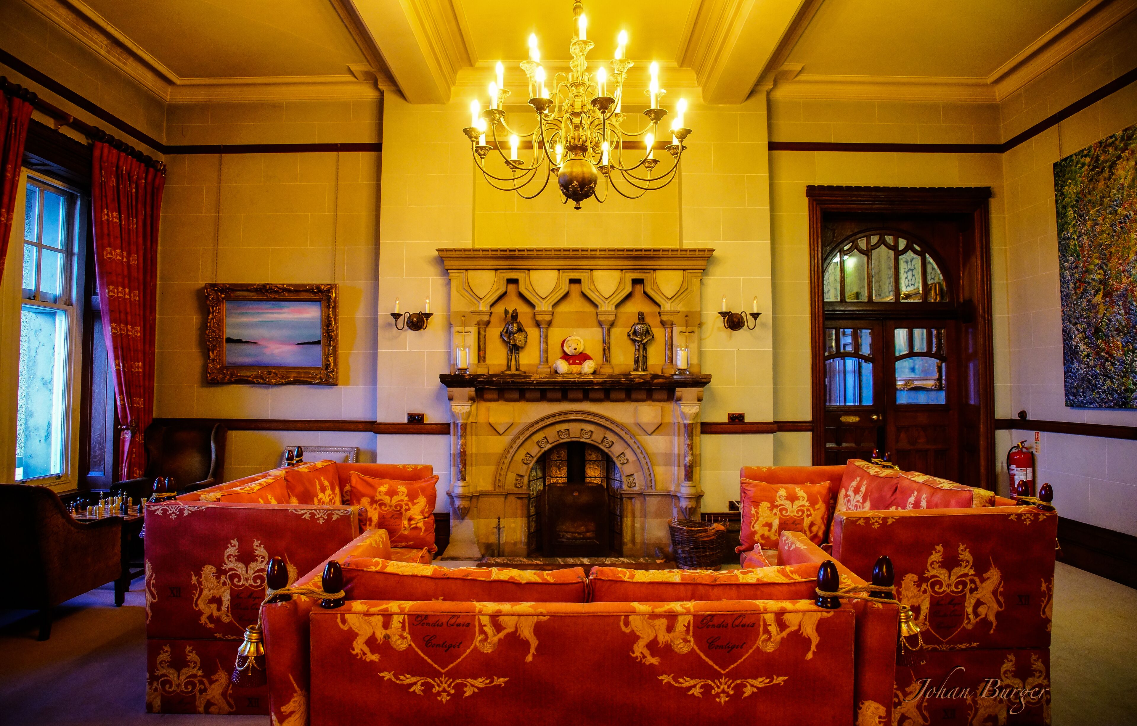 A grand room with a fireplace, ornate sofas, and a chandelier.