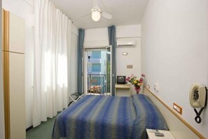A hotel room with a bed, a desk with a computer, a phone, and a window with curtains. - Hotel Sayonara (Cattolica)