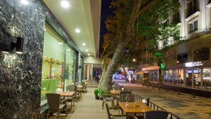 An outdoor cafe with tables and chairs, a tree, and a building with a restaurant sign. - The Parma Hotel Taksim (Istanbul)