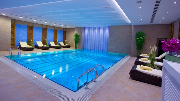A modern indoor swimming pool with lounge chairs and a tiled floor. - The Parma Hotel Taksim (Istanbul)