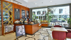 A Starbucks inside a building with a wooden counter, menu boards, and seating area with tables and chairs. - The Parma Hotel Taksim (Istanbul)