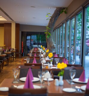 Ein Restaurant mit langen Tischen, violetten Servietten und gelben Blumen.