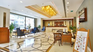 A hotel lobby with a reception desk, seating area, and a menu board. - The Parma Hotel Taksim (Istanbul)