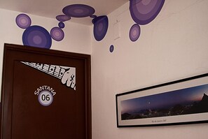 Eine Tür mit einem Aufkleber mit der Aufschrift "SANTANA 06" und einem gerahmten Bild einer Stadtansicht, beschriftet mit "Rio de Janeiro 360º", an der Wand.