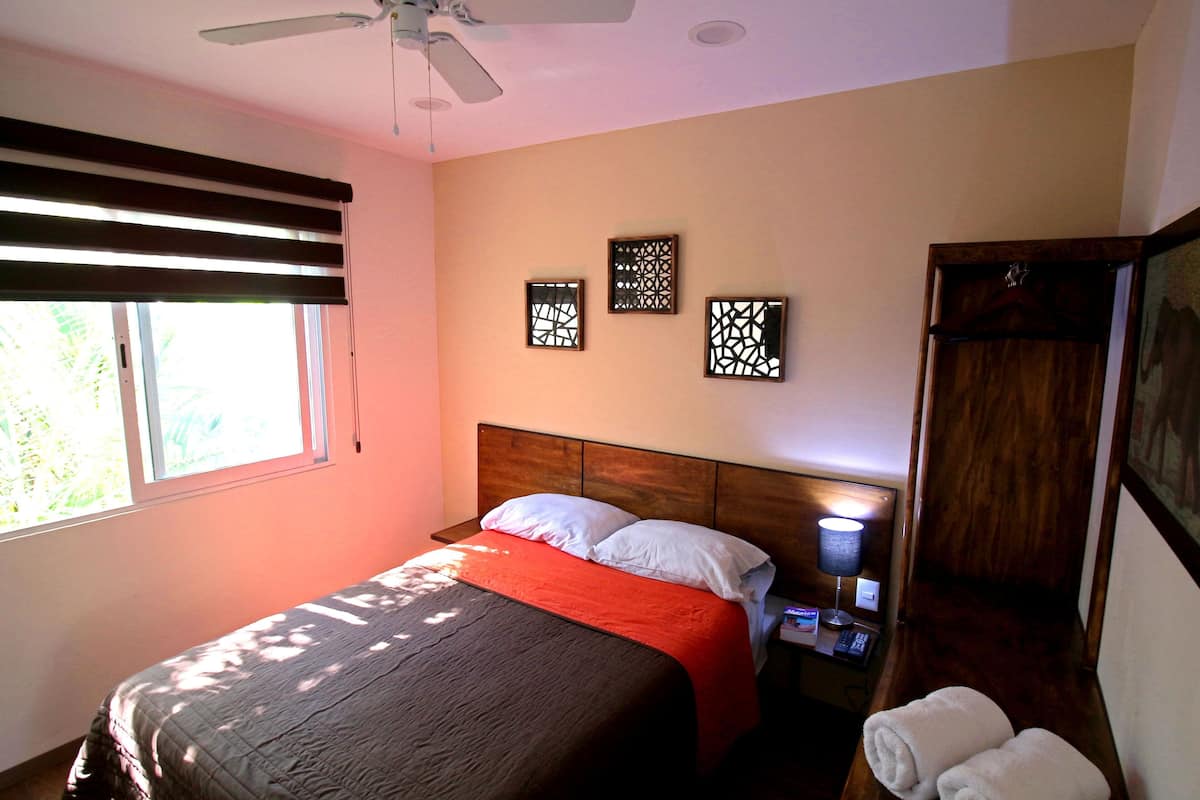 A bedroom with a bed, a nightstand, a lamp, a wardrobe, and decorative wall art.