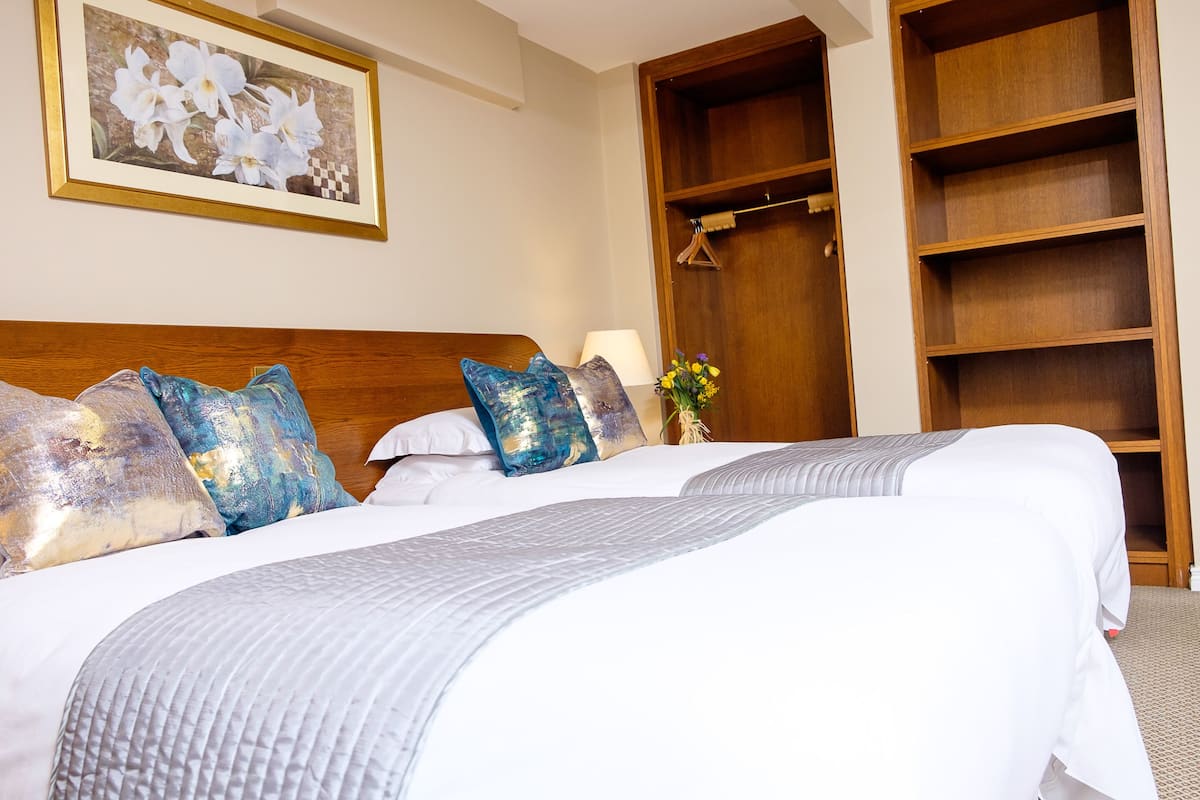 A neatly made bed with white and gray linens, a wooden headboard, and decorative pillows.