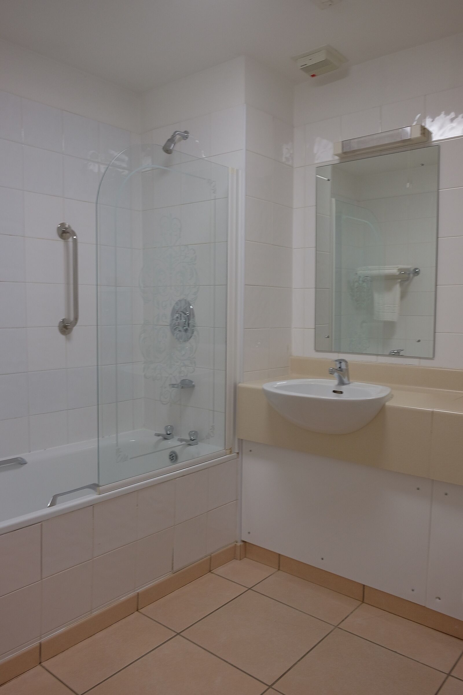 A bathroom with a glass-enclosed shower, a white sink, and a mirror above the sink.