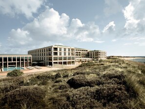 Un hotel moderno con varios pisos, piscina y vista al mar.