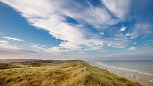 A beach with dunes and a clear sky.