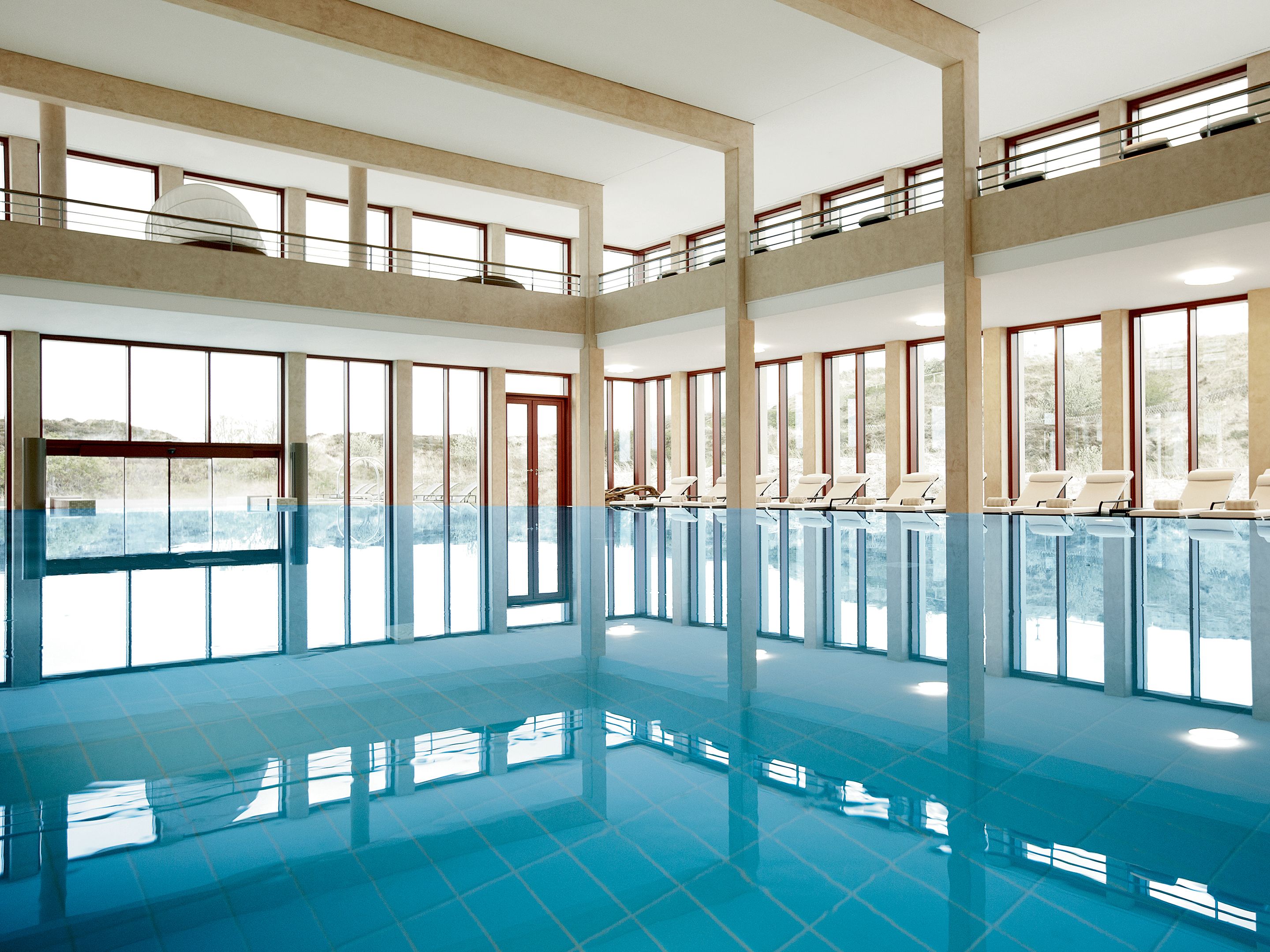 A large indoor swimming pool with multiple levels and sunlit windows.