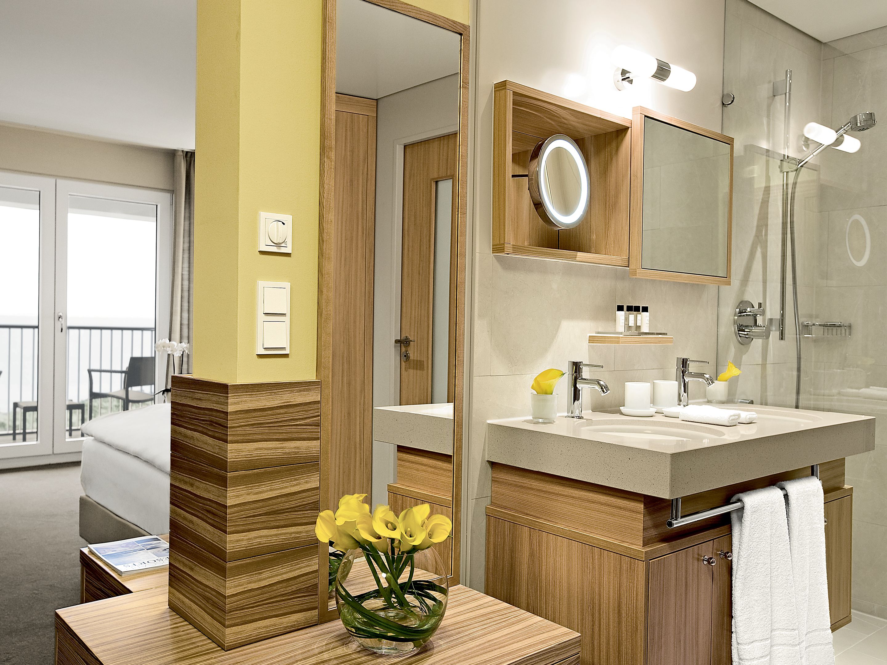 A modern bathroom with a wooden vanity, a large mirror, and a shower.